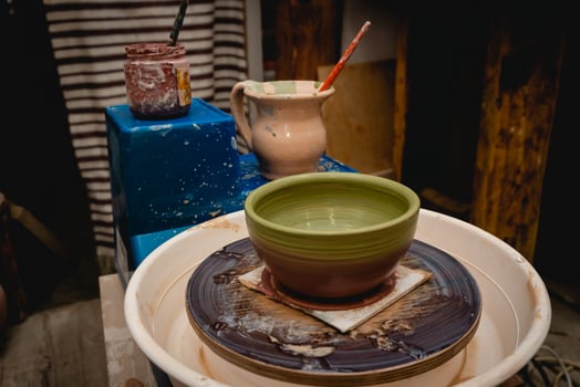 Potter working on potters wheel with clay. Process of making ceramic tableware in pottery workshop. photo