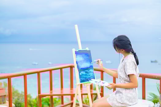 Young girl using brush drawing picture on canvas paper, at beautiful landscape view at koh tao Thailand. photo