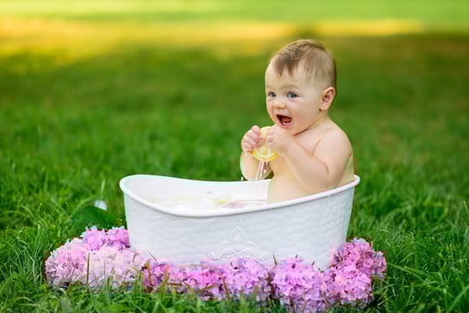 Little girl bathes in a milk bath in the park. The girl is having fun in the summer. photo