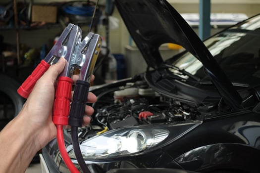 Hand holding Car battery charger over blurred car in garage background photo