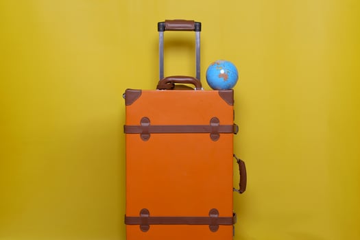Orange suitcase with mini globe isolated on yellow background for travel concept with minimal style photo