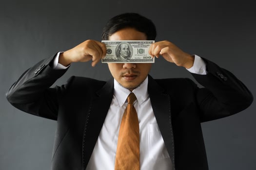 Greedy businessman in suit covering his eyes with dollar bills. Corruption and bribery concept photo