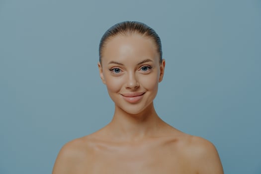 Beauty portrait of young smiling gorgeous woman with perfect clean healthy skin isolated on blue photo