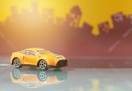 Orange saloon car toy selective focus on blur city background photo