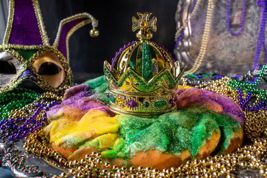Colorful king cake with crown surrounded by mardi gras beads photo