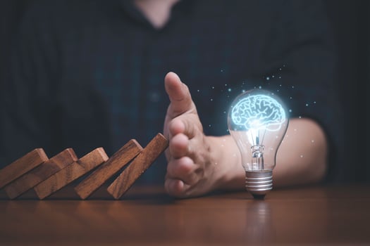 Hand protecting lightbulb with glowing virtual brain from falling wooden block , It is symbol of protect copyright and patent concept. photo