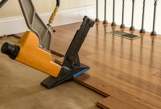 High pressure nail gun ready to install sections of Brazilian Cherry hardwood flooring photo