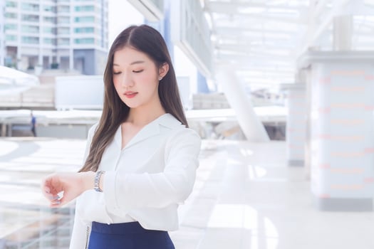Young business Asian woman is going to the office or workplace which she look at watch  in the big city with business buildings as a background. photo