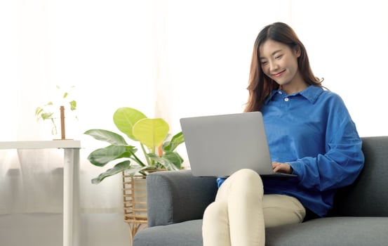 Young business freelance Asian woman working on laptop checking social media while lying on the sofa when relax in living room at home. photo
