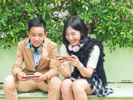 Young boy and girl play games on mobile phones photo