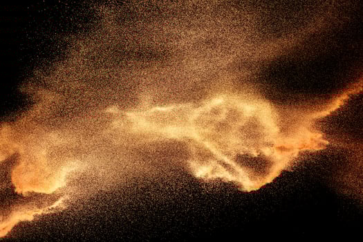 Abstract sand cloud.Brown sand splash against dark background. Brown dust explosion. photo