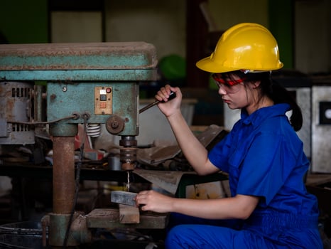 Asian women in mechanic uniforms are using power tools to drill metal bars in the factory photo