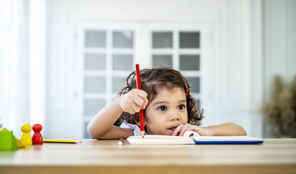 Cute little girl sit at desk at home doing homework, reading, writing and painting. Children paint. Kids draw. Preschooler with books at home. Preschoolers learn to write and read. Creative toddler photo