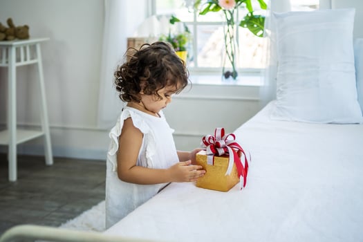 Pretty little girl happily after receiving the gift box in bed from her parents. due to birthday, Happy Holidays. Gift and present photo