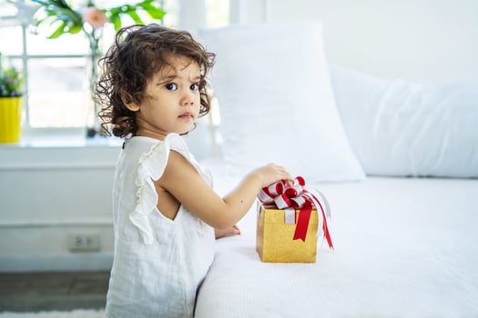 Pretty little girl happily after receiving the gift box in bed from her parents. due to birthday, Happy Holidays. Gift and present photo