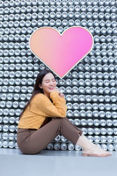 Asian pretty woman in long hair wears a yellow sweater and brightly smiles in Valentine s theme. photo