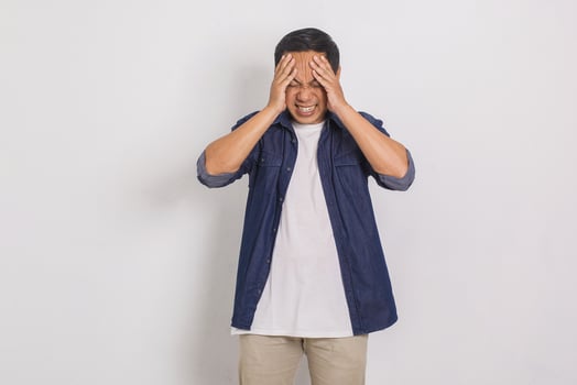 Portrait of handsome asian man dizzy while holding head with both hands isolated on white background photo