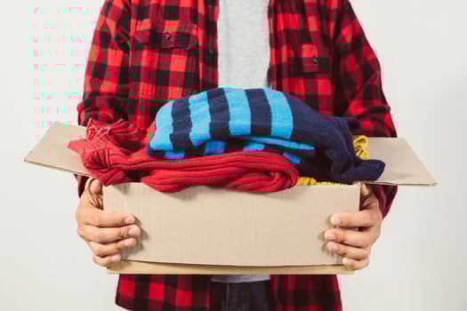 man holding a crate of second-hand clothes unused clothes photo