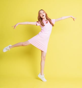 Full length image of young Asian girl standing on yellow background photo