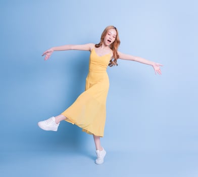 Full length image of young Asian woman wearing yellow dress on blue background photo