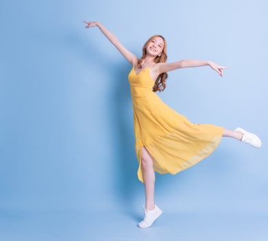 Full length image of young Asian woman wearing yellow dress on blue background photo