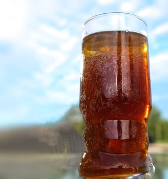 Refreshing orange summer cocktails with cola and ice against a blue sky background. Close up view. photo