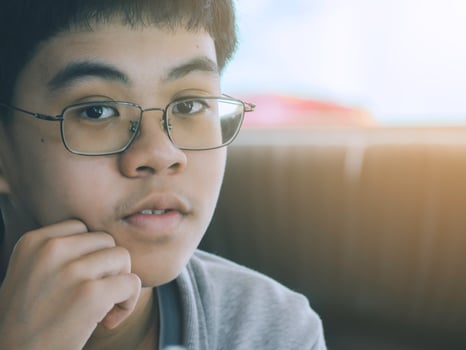 Thoughtful young boy wearing glasses in casual outfit thinking with an empty thought bubble. photo