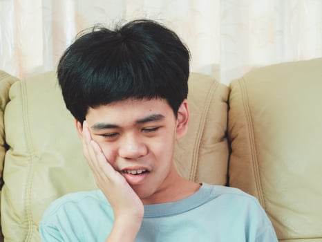 Little asia boy suffer from toothache. He sad with tooth pain, dental disease, kid suffering from dental problem. Plan to appointment dentist. photo