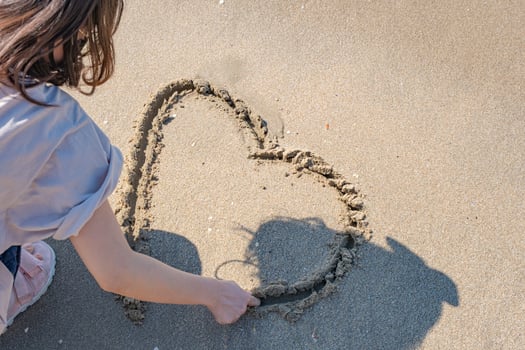 hand woman drawing hearts on the sand beach  at a beautiful seascape background. photo