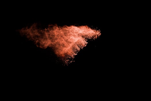 Orange color powder explosion on black background. photo