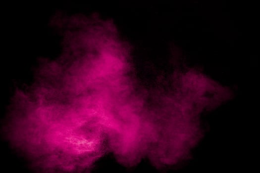 Pink dust particles splash on black background.Pink powder splash. photo