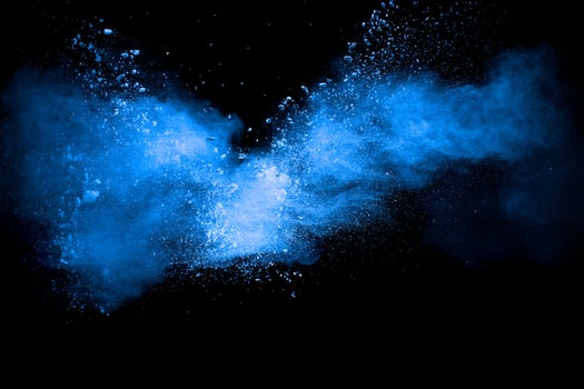 Blue color powder explosion cloud on black background.Closeup of Blue dust particles exhale. photo