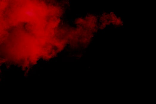 Red powder explosion on black background. Freeze motion of red dust particles splash. photo