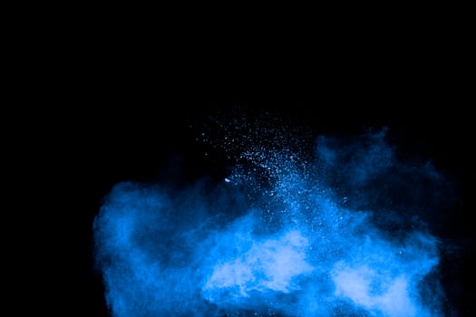 Blue powder explosion cloud on black background.Launched blue dust particles splash on background. photo