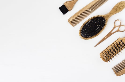 Golden hairdresser tools on a white background, scissors, comb, clip, brush. Hair salon accessories, template with space for text photo