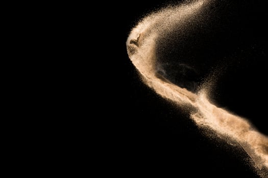 Dry river sand explosion. Golden colored sand splash agianst dark background. photo