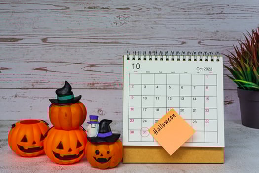 White October 2022 calendar with Jack o lantern pumpkin on wooden desk. photo