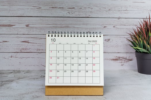 White October 2022 calendar with potted plant on wooden desk. 2022 new year concept photo
