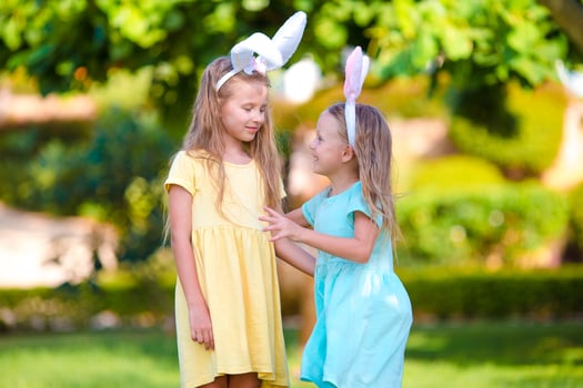 Two adorable little sisters wearing bunny ears on Easter day outdoors photo