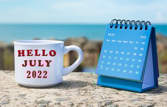 Hello July 2022 written on white coffee cup with blue calendar photo