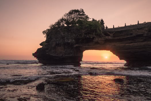 Sunset through of rocky cliff on seashore at sunset. Pura Batu Bolong, Bali photo