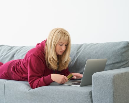 Mature woman online shopping, lying on couch with laptop and credit card. Middle-aged female photo