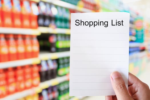 hand hold shopping list paper over soft drink bottles on shelves photo