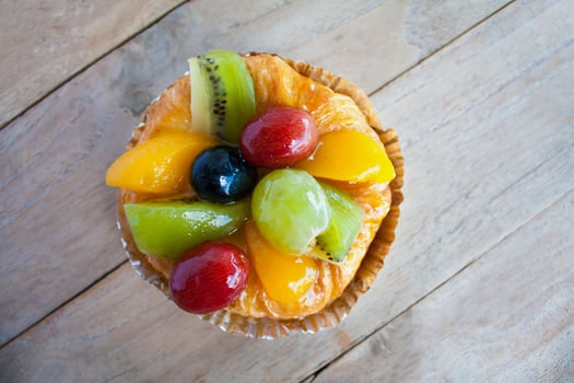 close up danish pastry with fruit on wood table photo