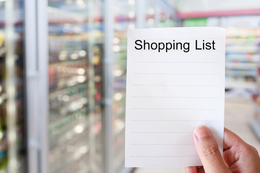 hand holding shopping list paper with convenience store shelves photo