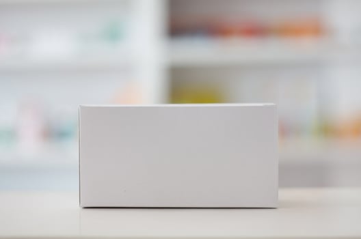 white blank medical packaging with pharmacy shelves background photo
