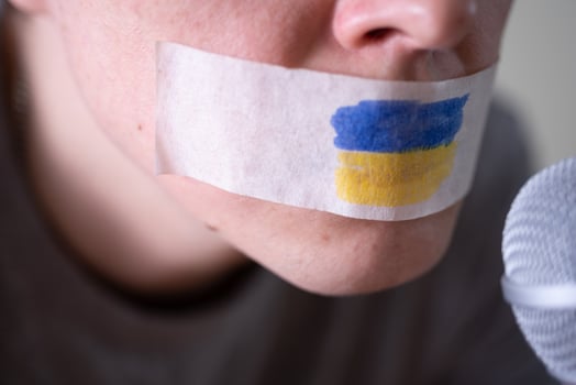 Tape over his mouth with the flag of Ukraine, trying to speak into a microphone. photo