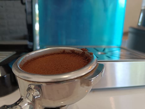 Portafilter with coffee powder on white table photo
