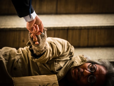 A businessman gives money to a homeless man sleeping on a ladder photo
