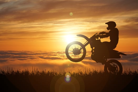 Silhouette of a motocross motorcycle lifting the front wheel. Adventure and Action Concepts photo
